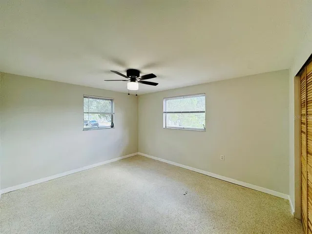an empty room with a window and a ceiling fan