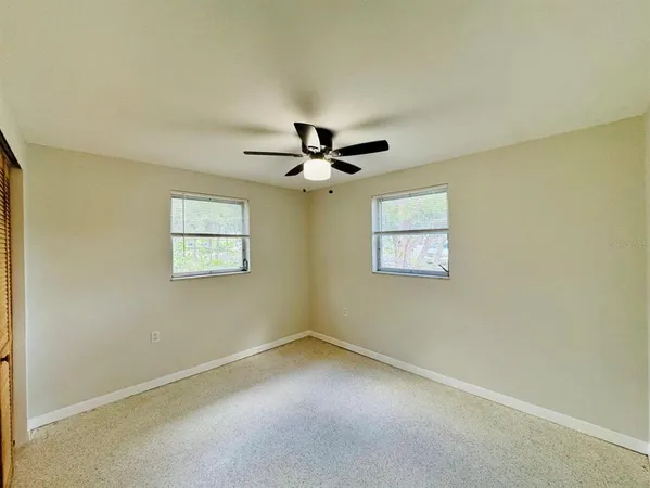 an empty room with a window and a ceiling fan