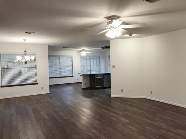 an empty room with wooden floor fireplace and ceiling fan