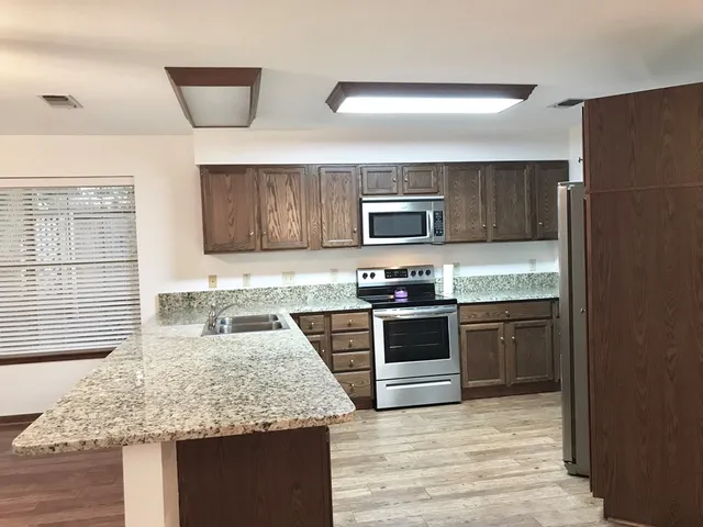 a kitchen with granite countertop stainless steel appliances and wooden cabinets