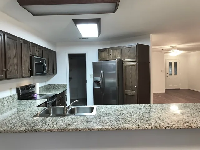 a kitchen with stainless steel appliances granite countertop a refrigerator a stove a sink and a microwave