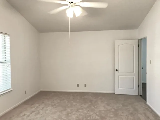 an empty room with a fan & a window