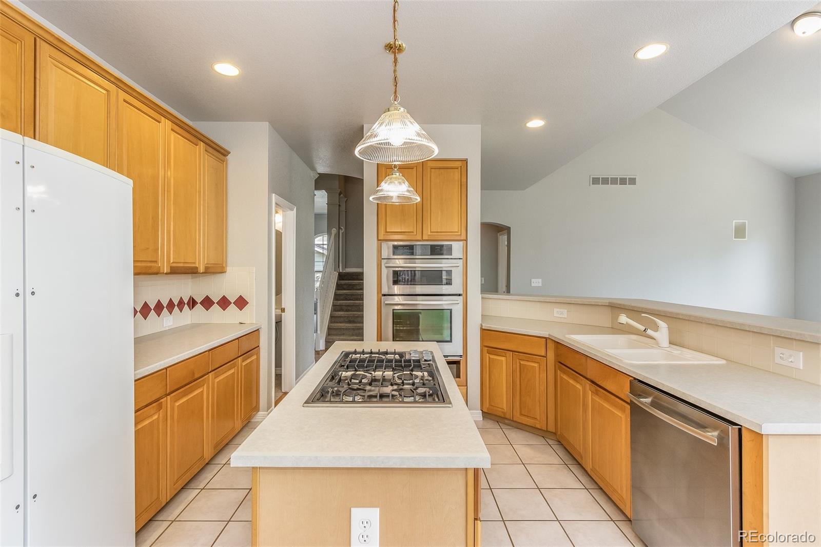 424 Whitetail Circle Lafayette, CO 80026 - Photo 4 of 19 a large kitchen with stainless steel appliances granite countertop a stove a sink dishwasher and a refrigerator with wooden floor