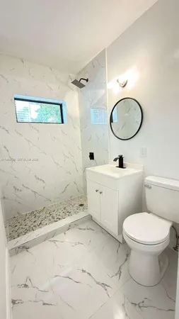 a bathroom with a granite countertop toilet sink mirror and shower
