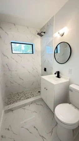 a bathroom with a granite countertop toilet a sink and mirror