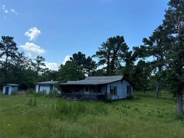 a view of a barn house in the middle of a green field