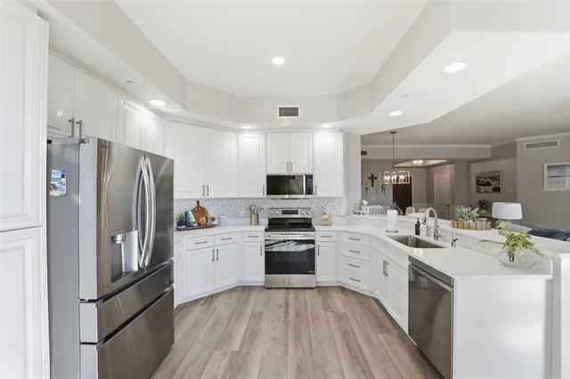 a kitchen with stainless steel appliances a stove a sink dishwasher a refrigerator and a oven with white cabinets
