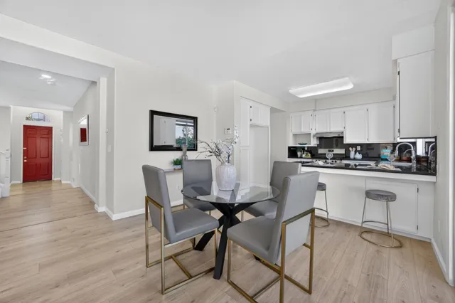 a kitchen with stainless steel appliances kitchen island granite countertop a table chairs cabinets and wooden floor