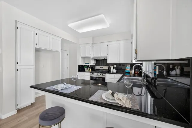 a kitchen with stainless steel appliances granite countertop a sink a stove and a refrigerator