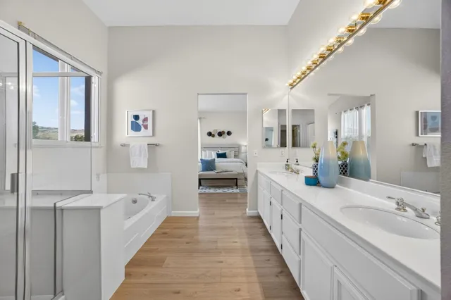 a large white bathroom with a double vanity sink a mirror and a bathtub