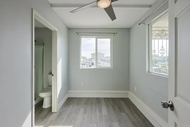 a view of an empty room with a window and wooden floor