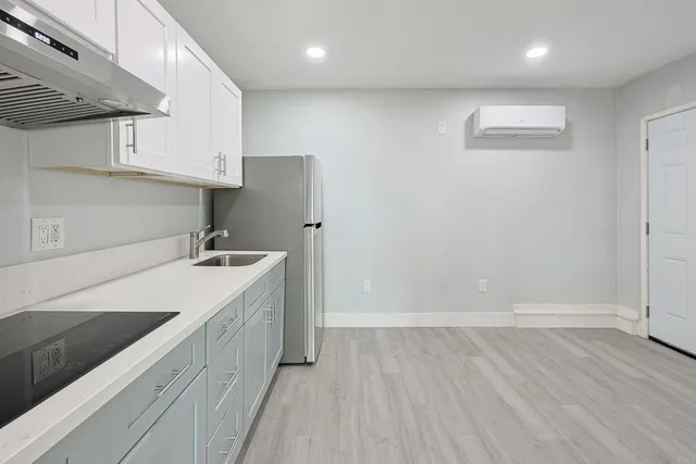 an empty room with wooden floor and sink