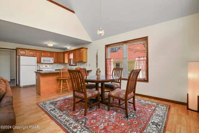 a kitchen with stainless steel appliances granite countertop a refrigerator a stove a sink a dining table and chairs with wooden floor