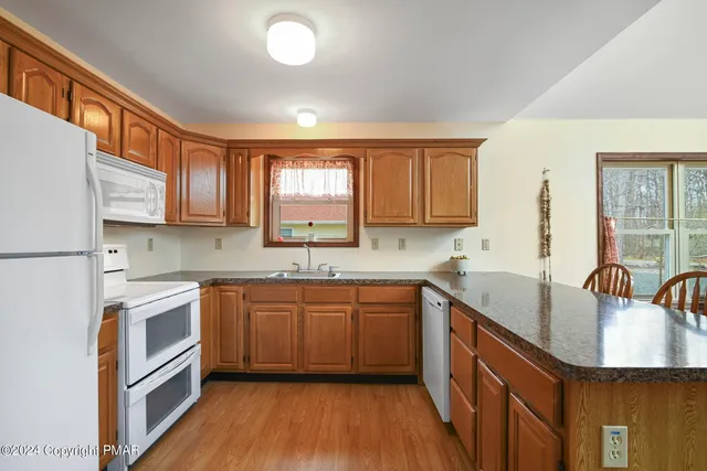 a dining hall with granite countertop a stove a sink dishwasher a dining table and chairs with wooden floor