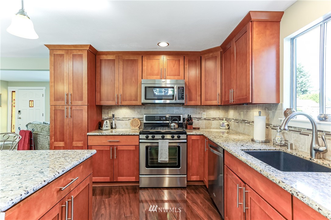 7007 Carson Road Everett, WA 98203 - Photo 8 of 24 a kitchen with stainless steel appliances granite countertop a stove a sink dishwasher and cabinets with wooden floor