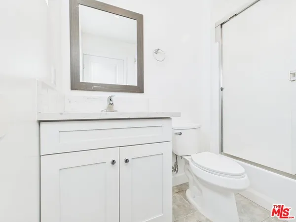 a bathroom with a toilet sink vanity and mirror