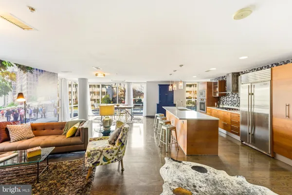 a kitchen with stainless steel appliances kitchen island granite countertop a refrigerator a stove a microwave oven a dining table and chairs with wooden floor