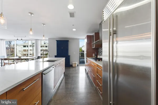 a large kitchen with kitchen island a large counter top stainless steel appliances and cabinets