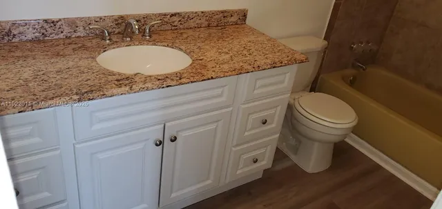 a bathroom with a granite countertop toilet sink mirror and vanity