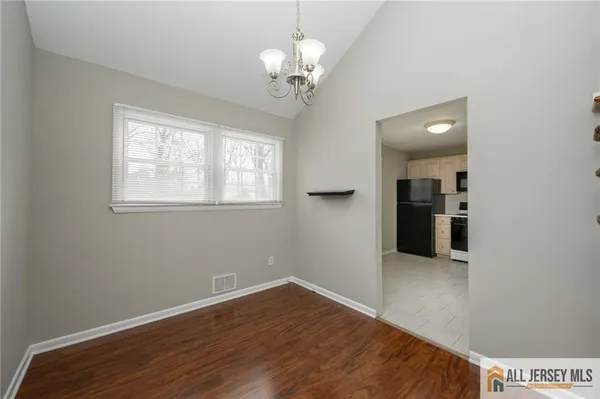 an empty room with wooden floor cabinet and windows