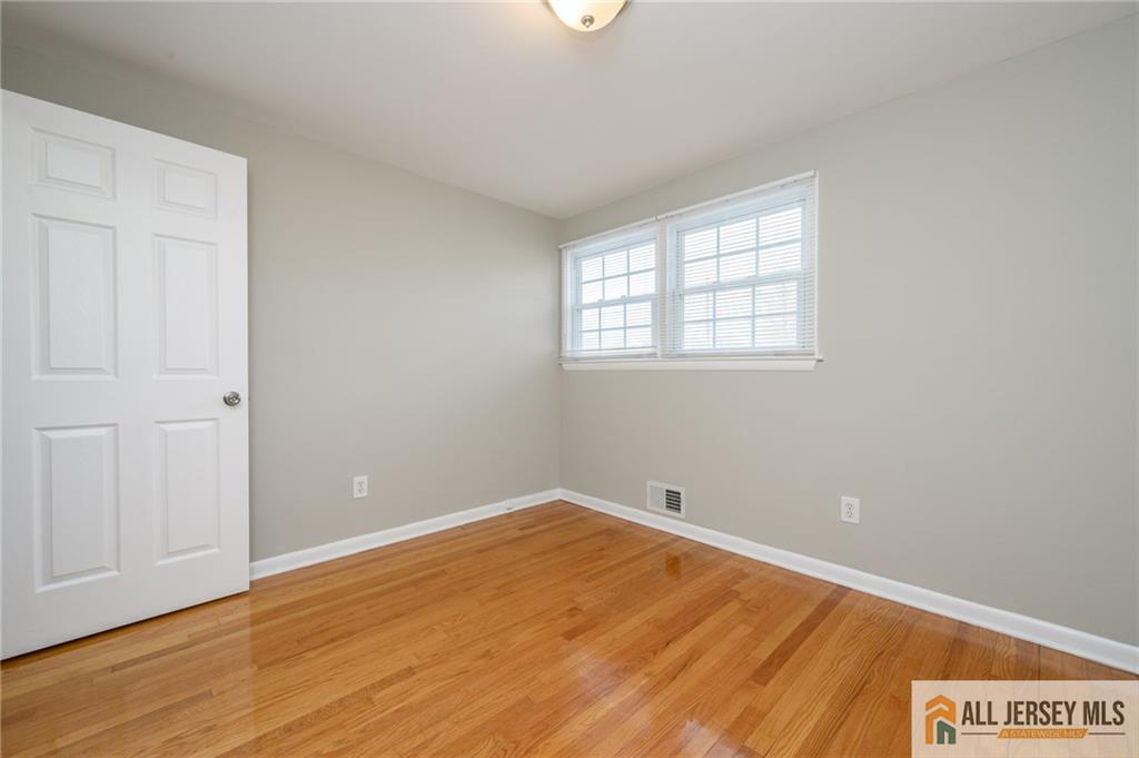 691 Inman Avenue Colonia, NJ 07067 - Photo 23 of 32 an empty room with wooden floor and windows