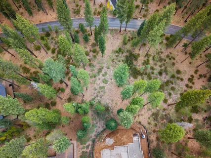 an aerial view of residential house with outdoor space and trees all around