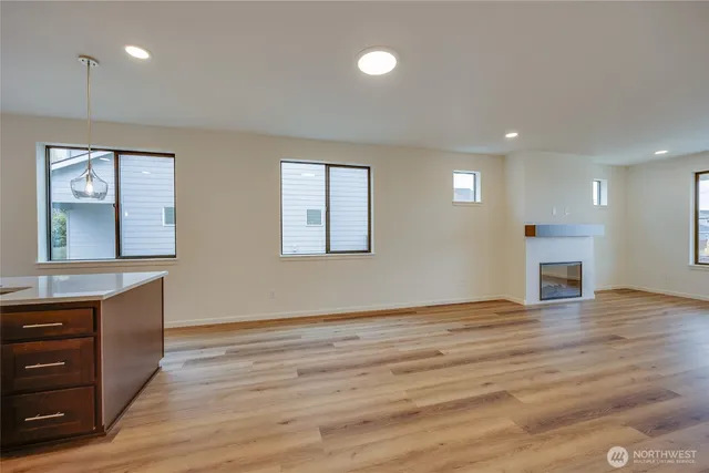 an empty room with wooden floor cabinet and windows