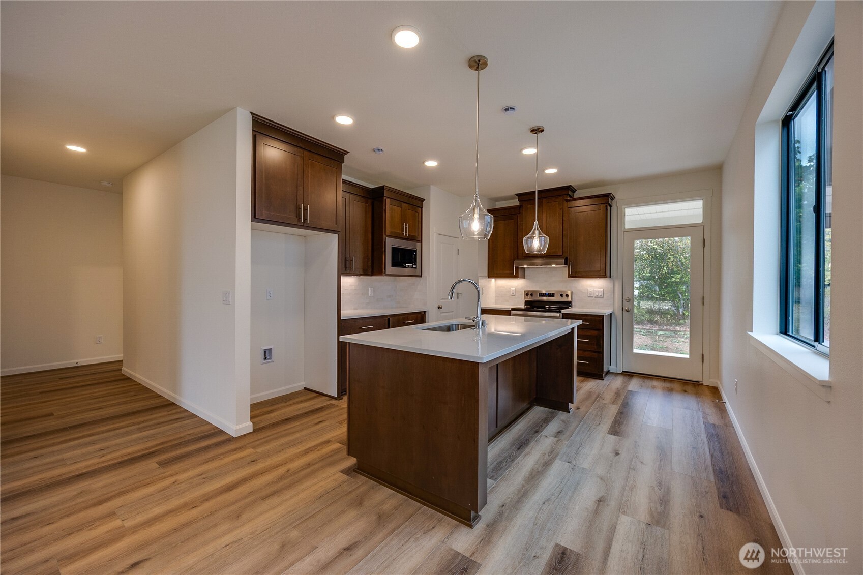 950 RW Fletcher Street Winlock, WA 98596 - Photo 7 of 40 a kitchen with kitchen island a sink wooden floor and stainless steel appliances