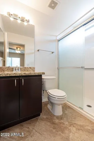 a bathroom with a granite countertop sink a toilet a mirror and bathtub