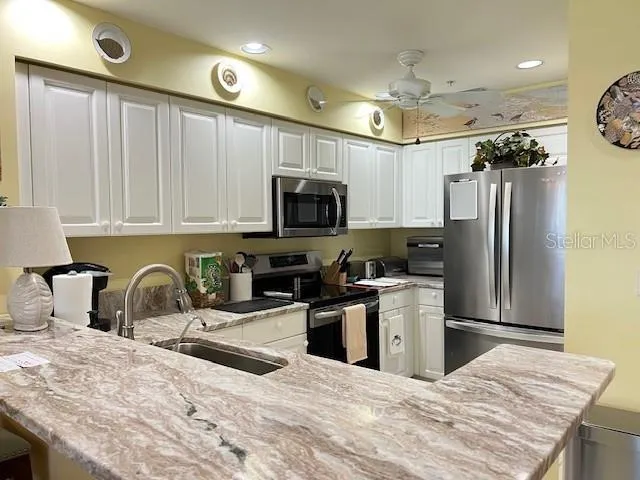 a kitchen with granite countertop a stove sink and refrigerator