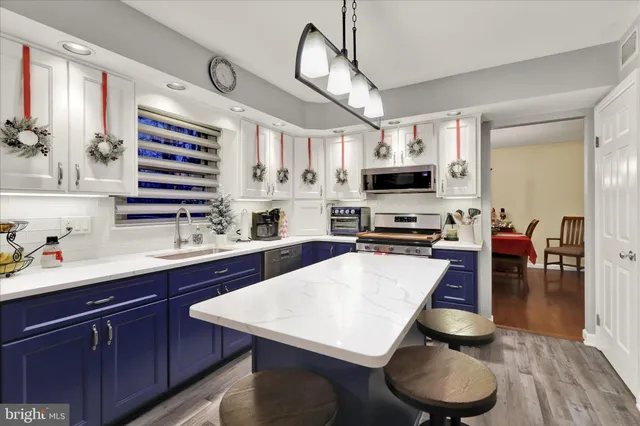 a kitchen with stainless steel appliances granite countertop a stove a sink dishwasher a dining table and chairs with wooden floor