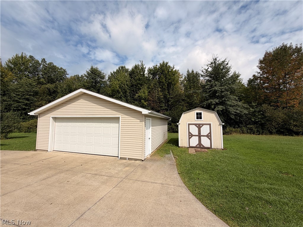 7213 Davis Road Orwell, OH 44076 - Photo 22 of 24 Detached garage with horizontal siding, a white sectional garage door, and a side entry door