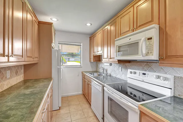 a kitchen with granite countertop a sink a stove and a microwave oven in a cabinets