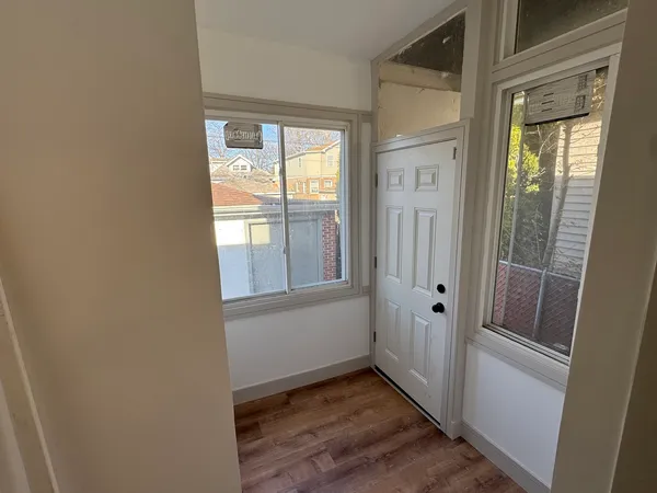 a view of an empty room with wooden floor and a window