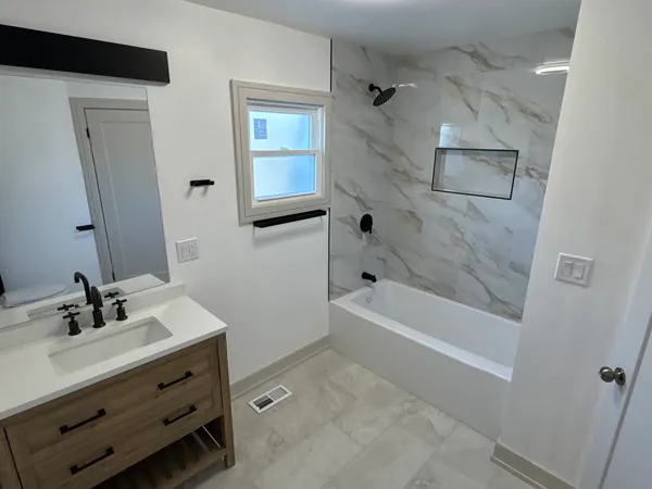 a bathroom with a bathtub sink vanity and mirror