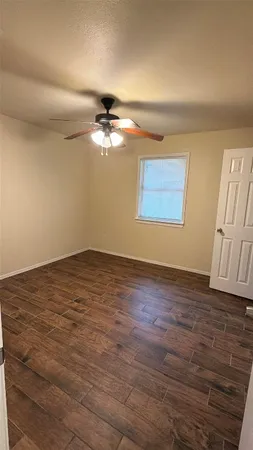 an empty room with wooden floor chandelier fan and windows