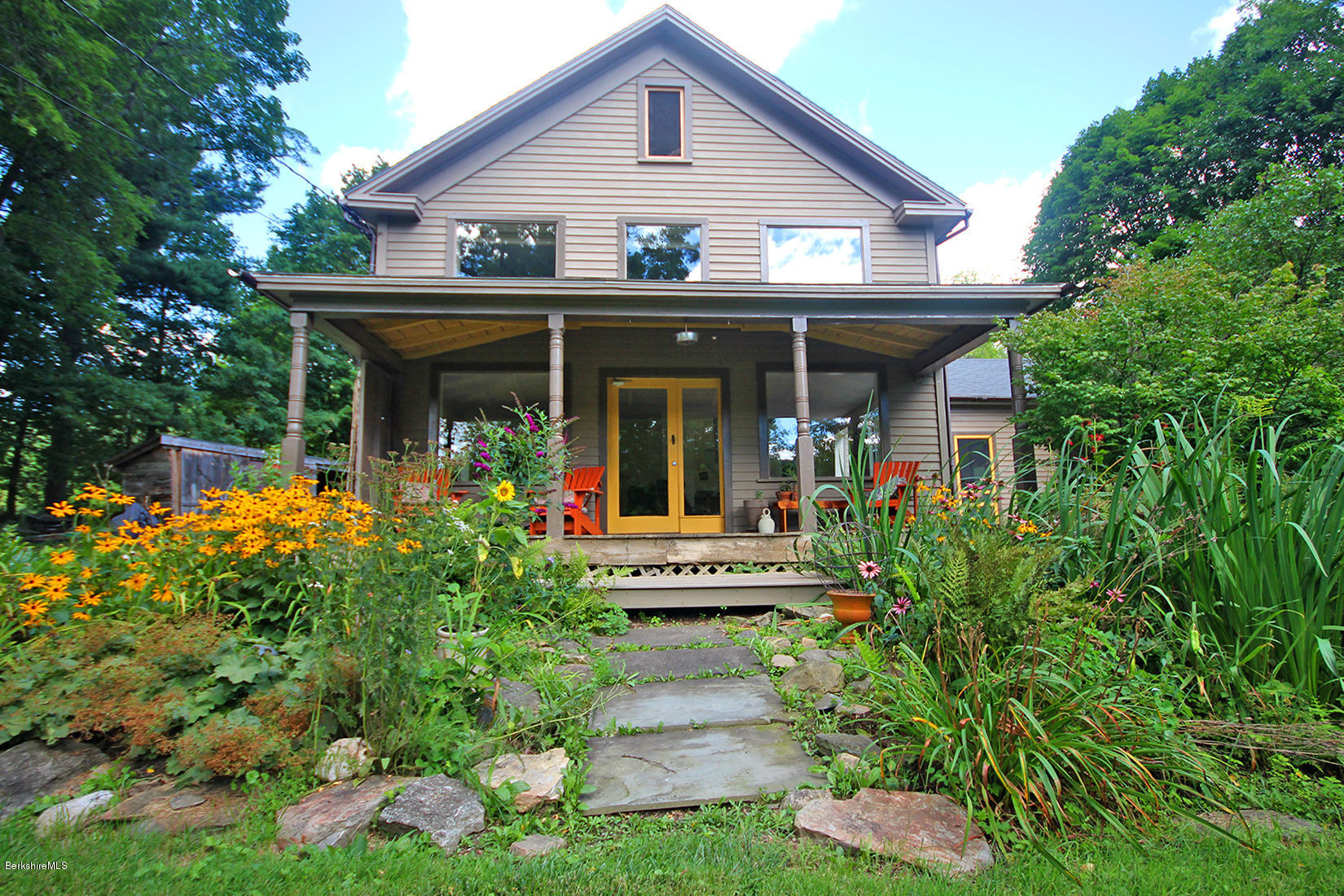 47 Main Road Tyringham, MA 01238 - Photo 2 of 31 a view of a white house with potted plants and a table and chairs