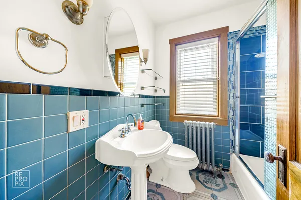 a bathroom with a sink a mirror a toilet and a window