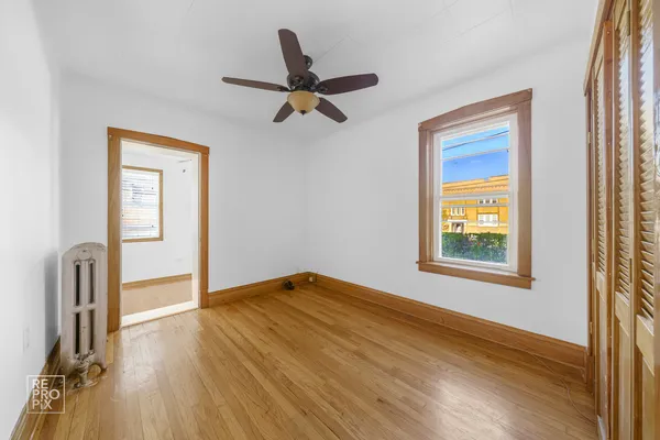 a view of empty room with wooden floor and fan