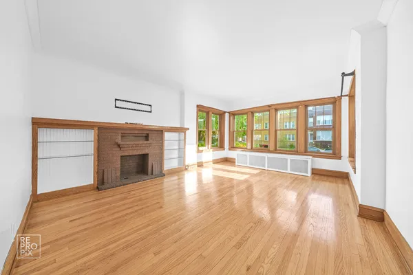 wooden floor fireplace and windows in an empty room