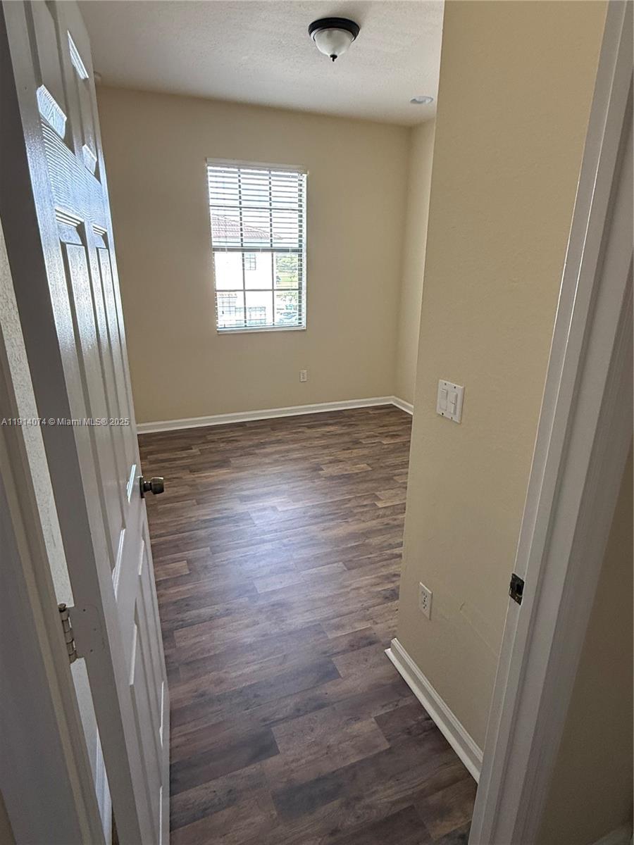 1713 Southwest Umbria Street, Unit 1713 Port St. Lucie, FL 34953 - Photo 11 of 17 a view of an empty room with wooden floor and a window