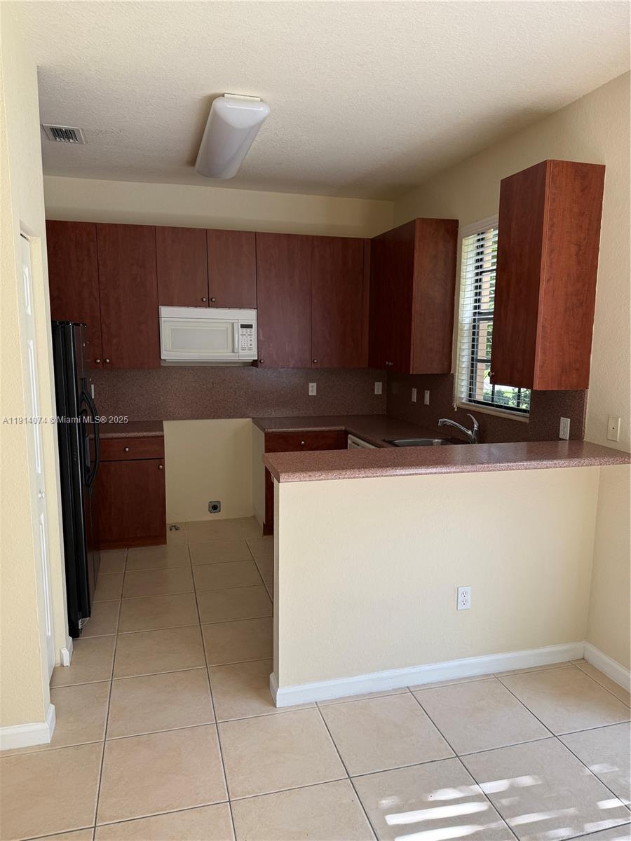 1713 Southwest Umbria Street, Unit 1713 Port St. Lucie, FL 34953 - Photo 6 of 17 a kitchen with stainless steel appliances a refrigerator sink and cabinets
