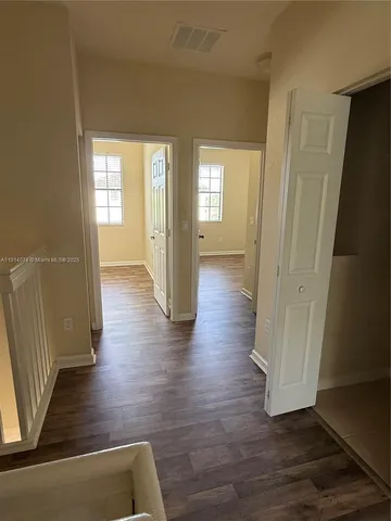 a view of a hallway with wooden floor and stairs
