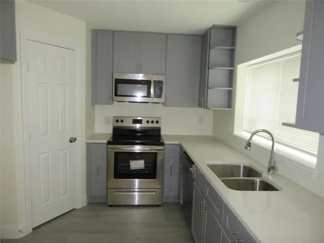 a kitchen with stainless steel appliances a sink a stove and microwave