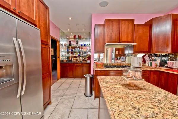 a kitchen with stainless steel appliances kitchen island granite countertop a refrigerator and cabinets