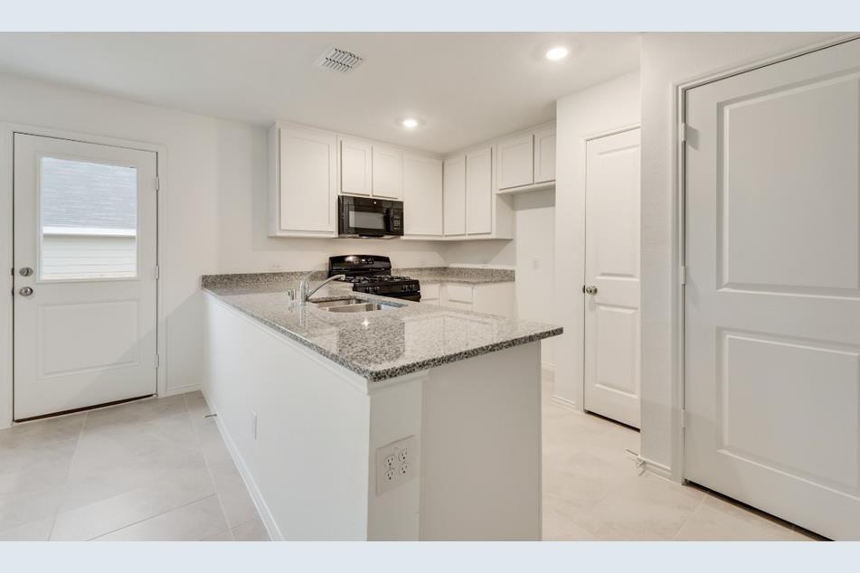 9832 Trusler Road Fort Worth, TX 76179 - Photo 6 of 13 a kitchen with stainless steel appliances granite countertop a sink a stove a refrigerator a microwave a sink and white cabinets