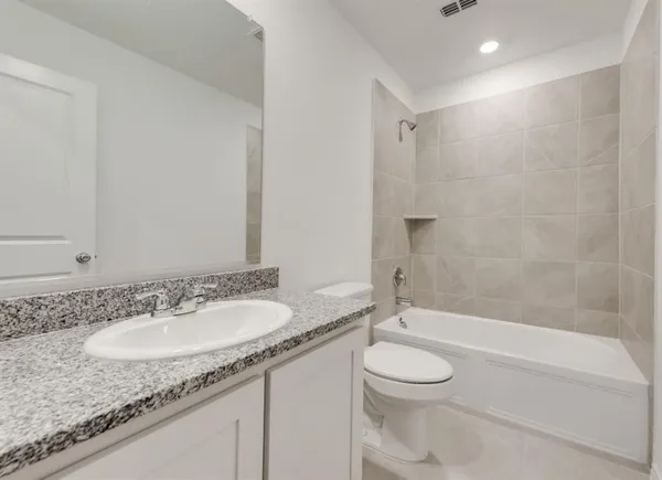a bathroom with a granite countertop sink toilet a mirror and a bathtub
