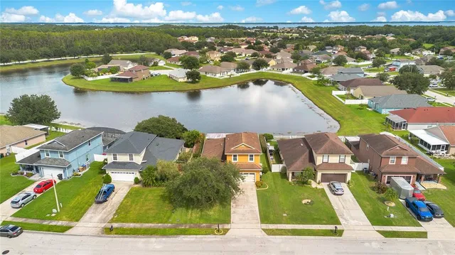 an aerial view of residential houses with outdoor space and lake view