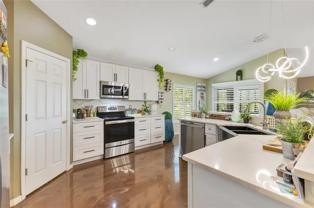 a kitchen with a refrigerator a stove top oven a sink a dining table and chairs