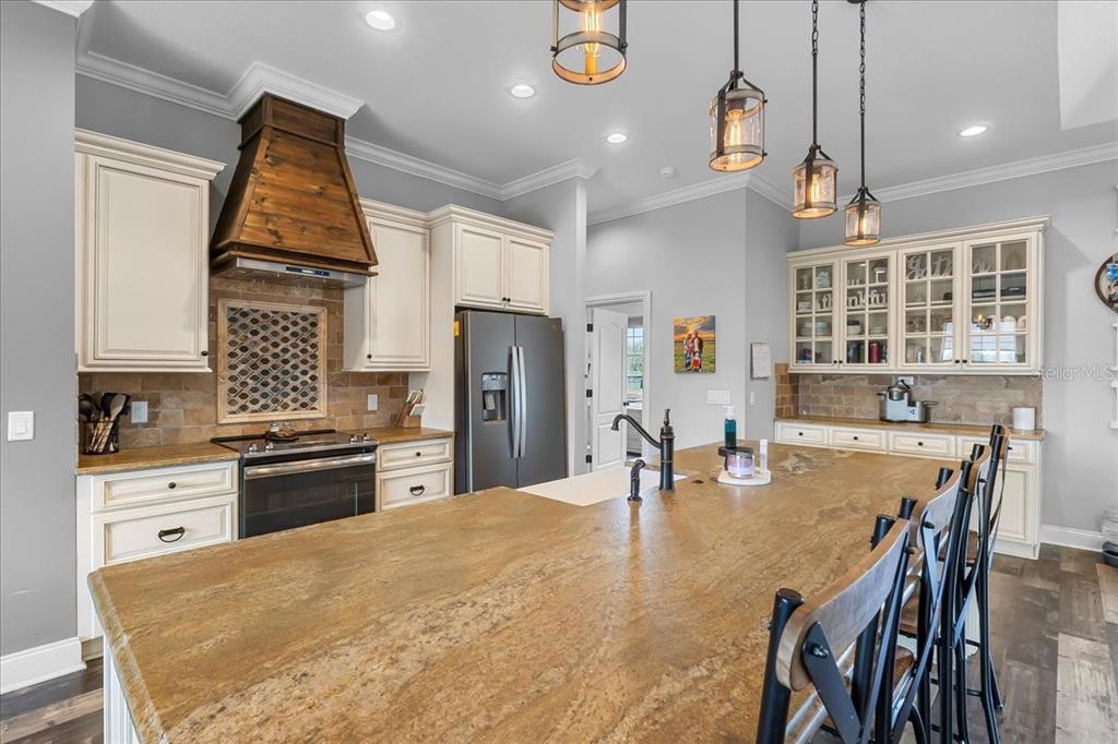 11657 Moore Road Lakeland, FL 33809 - Photo 55 of 100 a kitchen with stainless steel appliances granite countertop a stove refrigerator a dining table and chairs with wooden floor